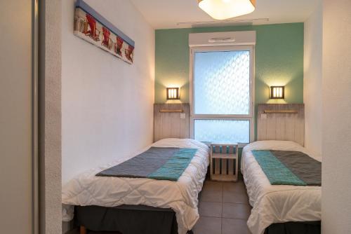 deux lits dans une chambre avec une fenêtre dans l'établissement Liorzh - Appt proche plage idéal pour familles, à Bénodet