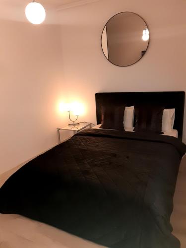 ein Schlafzimmer mit einem schwarzen Bett und einem Spiegel in der Unterkunft MIA PLUS!! self check-in!! in Bukarest