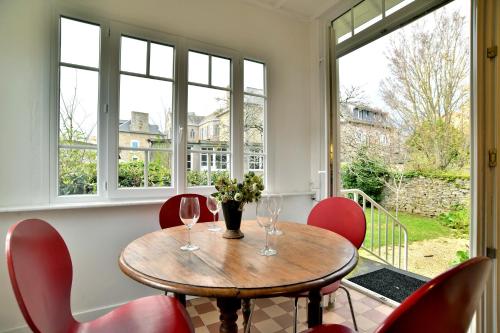 une salle à manger avec une table, des chaises et des fenêtres dans l'établissement La Brise Cancalaise - Maison typique avec vue mer, à Cancale
