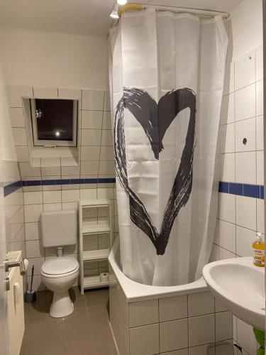 a bathroom with a toilet and a shower curtain with a heart at Balance Apartments by M&A - Train station in Witzenhausen