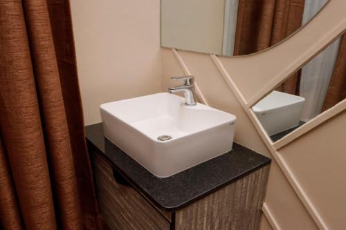 ein Badezimmer mit einem weißen Waschbecken und einem Spiegel in der Unterkunft Lux Suites Nakuru VIP Suites in Nakuru