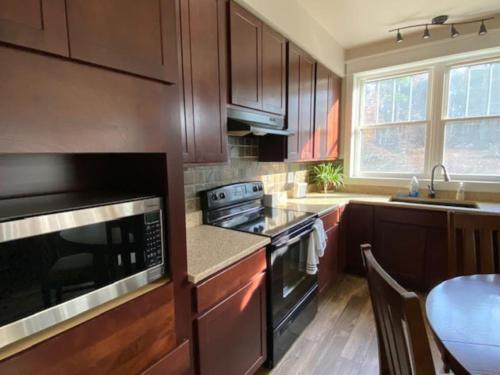 uma cozinha com armários de madeira e um forno com placa de fogão em An Adirondack Getaway em Keeseville