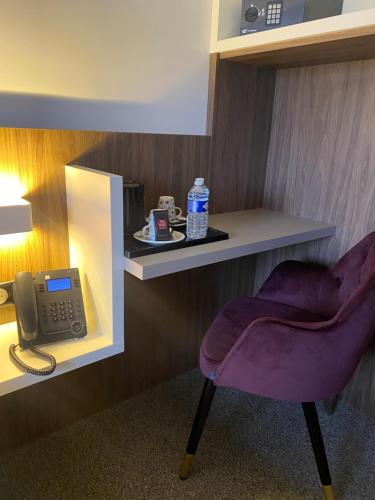 a room with a purple chair and a phone at Hôtel du Château in Villers-lès-Nancy