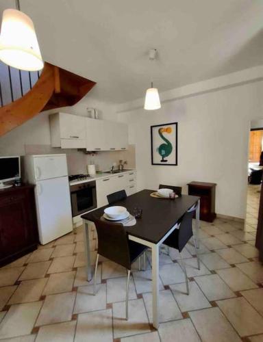 Appartamento in centro في تورتونا: مطبخ مع طاولة وكراسي في غرفة