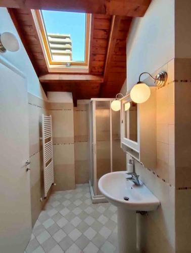 een badkamer met een wastafel, een douche en een raam bij Appartamento in centro in Tortona