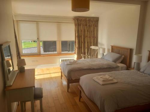 1 dormitorio con 2 camas, escritorio y 2 ventanas en Monterno, Luxury Accommodation Glengarriff, County Cork - Sleeps 8, en Glengarriff