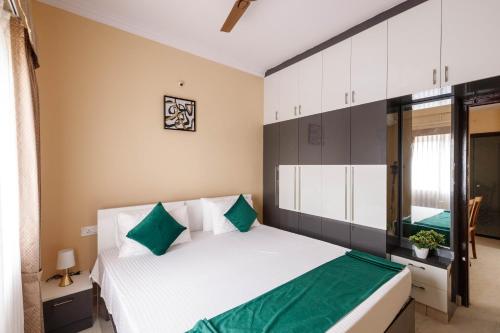 a bedroom with a large white bed with green pillows at Elite Peak Serviced Apartments in Bangalore