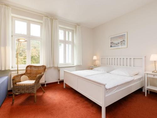 una camera con letto bianco, sedia e finestre di Apartment Zinnowitzer Hof-3 by Interhome a Zinnowitz