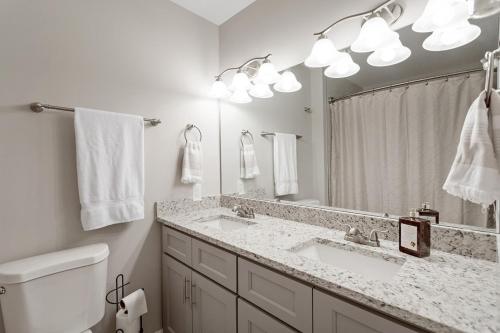 uma casa de banho branca com 2 lavatórios e um espelho em Garner Relaxing Stay em Garner