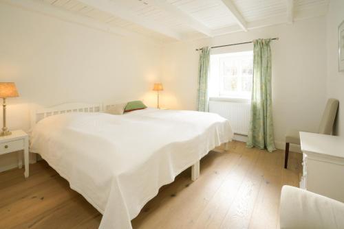 a white bedroom with a large white bed and a window at Strandhaus Falshöft 3 in Nieby