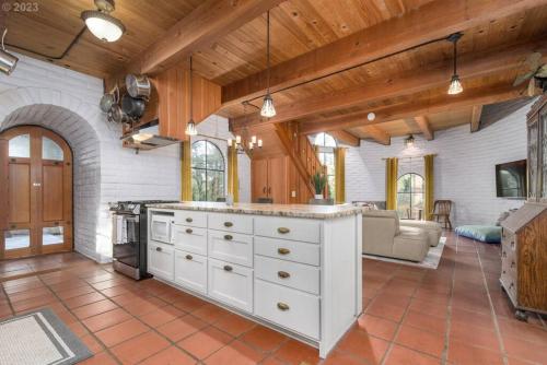 eine Küche mit weißen Schränken und ein Wohnzimmer in der Unterkunft Le Chateau de Laurelwood in Eugene
