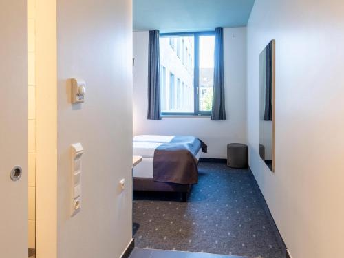 een ziekenhuiskamer met een bed en een raam bij B&B Hotel München-Trudering in München