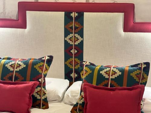 a bed with two pillows and a red head board at Posada de los Venerables in Seville