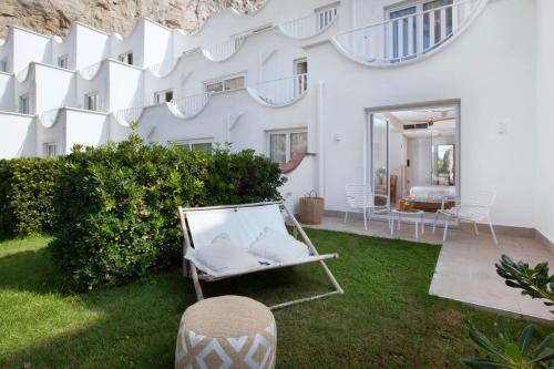 a white house with a chair in the yard at Maya Beach Resort in Massa Lubrense