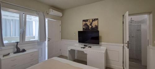 um quarto branco com uma televisão e uma secretária branca em Sea view sol & mar em Rabil