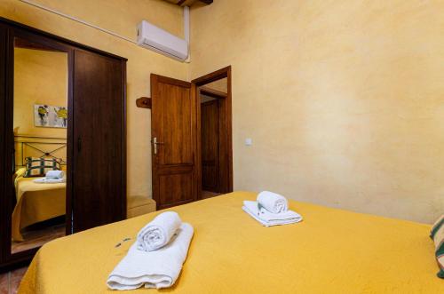 um quarto com uma cama amarela com toalhas em YourHouse Cas Padri de Inca em Inca