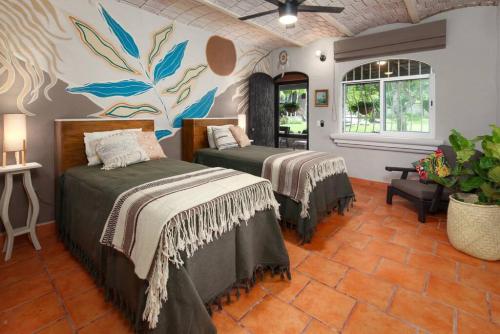 サユリタにあるBeautiful 4-Bedroom Hacienda, 5-Minutes from Beachのベッドが2つあり、壁に絵が飾られた寝室