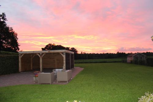 a tent in a field with a sunset in the background at B&B 't Mjeels Pierke in Meerle