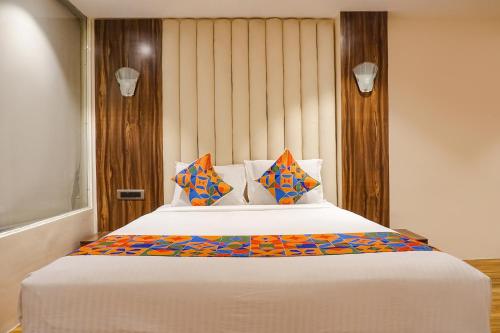 a bedroom with a large white bed with colorful pillows at FabHotel Dreams Inn in Pune