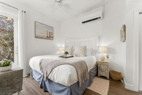 a white bedroom with a bed and a window at Villages B293 apts in Rosemary Beach
