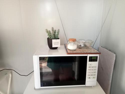 a white microwave with a plant on top of it at The City Dweller Kingaroy in Kingaroy