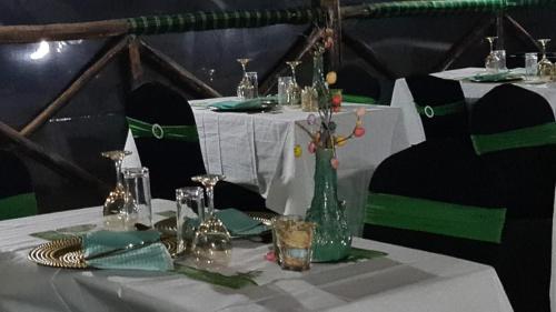 a table with a white table cloth and a green vase at Amanya 1-Bed Elephant Suite Tent in Amboseli