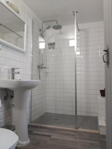 uma casa de banho branca com um chuveiro e um lavatório. em Casas do Patheo em Gaieiras