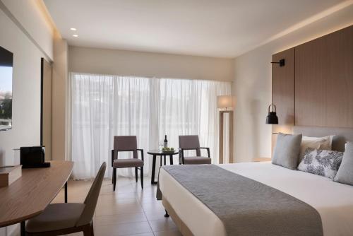 a hotel room with a bed and a table and chairs at Atlantica Bay - Adults Only in Limassol