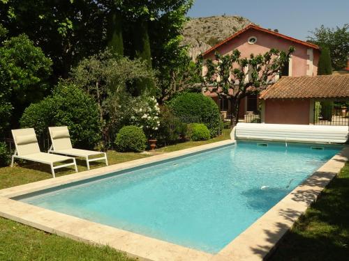 une piscine avec deux chaises et une maison dans l'établissement Élégante demeure à Cavaillon avec piscine, parc arboré et climatisation, proche centre-ville - FR-1-708-49, à Cavaillon