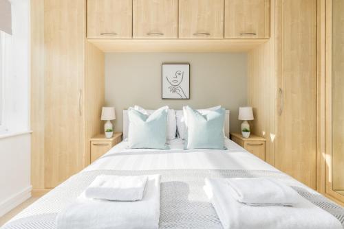 1 dormitorio con 1 cama blanca grande con almohadas azules en The Wembley Collection, en Londres