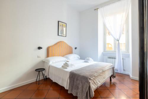 a white bedroom with a bed and a window at Colosseo 85 in Rome
