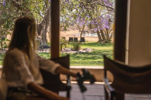 a woman sitting in a chair in front of a window at Last Word Madikwe in Madikwe Game Reserve