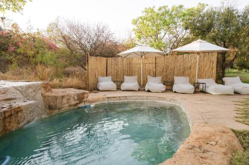 a swimming pool with an umbrella and some chairs and an umbrella at Last Word Madikwe in Madikwe Game Reserve