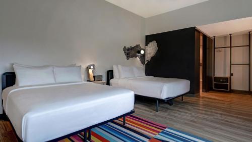 a hotel room with two beds and a chair at Aloft Mooresville in Mooresville