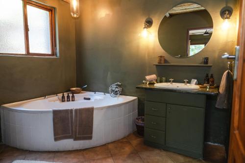 a bathroom with a tub and a sink and a mirror at Last Word Madikwe in Madikwe Game Reserve