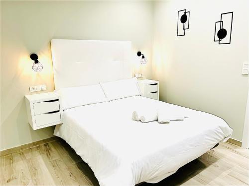 1 dormitorio blanco con 1 cama blanca y 2 mesitas de noche en RIBERA HOME 2 en Córdoba