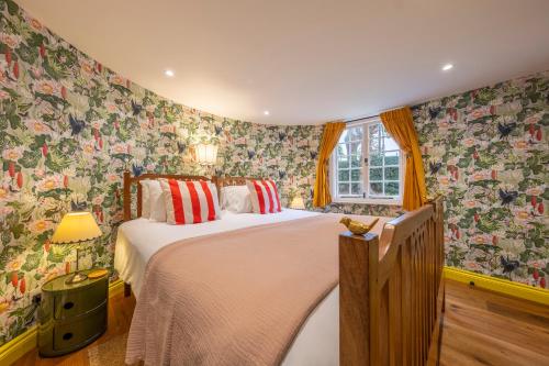 a bedroom with a large bed with floral wallpaper at A fairy-tale luxurious cottage - The Tea Caddy in Colchester