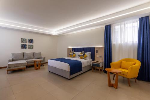 Premium Inn Mombasa City في مومباسا: غرفة نوم بسرير واريكة وكرسي