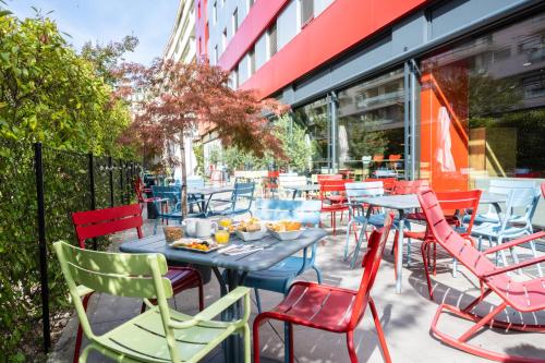 une terrasse avec des chaises et des tables colorées en face d'un bâtiment dans l'établissement ibis Genève Centre Nations, à Genève