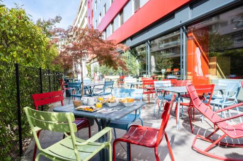 a patio with colorful chairs and tables in front of a building at ibis Genève Centre Nations in Geneva