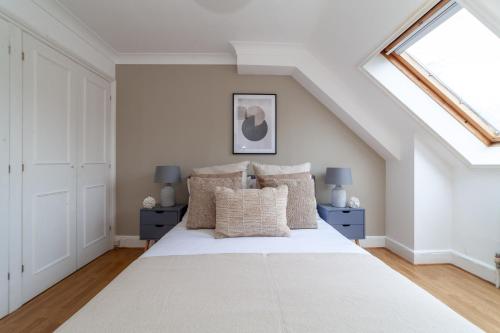 a bedroom with a large white bed and a skylight at The Lewisham Flats in London