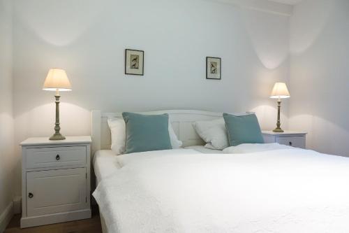 ein Schlafzimmer mit einem weißen Bett und zwei Lampen in der Unterkunft Kätchen am Schlossgraben - Schloss Gelting in Gelting