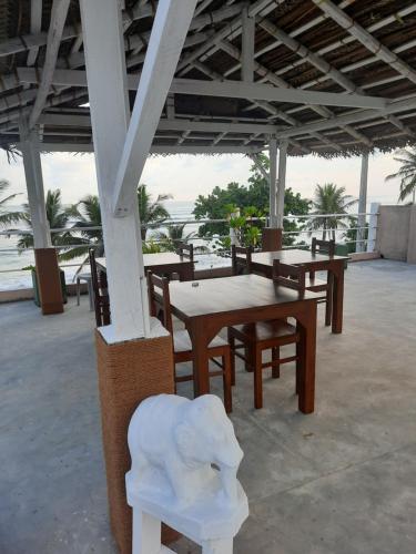 una mesa y sillas sentadas bajo un pabellón en White Surfing Beach Resort, en Unawatuna