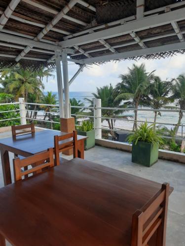 a table and chairs on a patio with the beach at White Surfing Beach Resort in Unawatuna