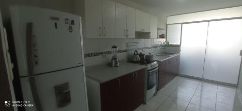 een witte keuken met een koelkast en een fornuis bij Angélica in Miraflores