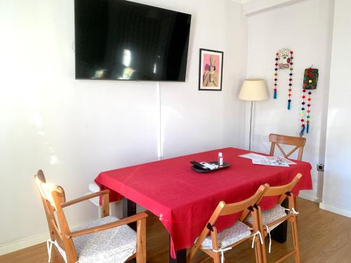 a dining room with a red table with chairs and a television at Un hogar en el centro - La Casa de Ion Parking gratuito in Zaragoza