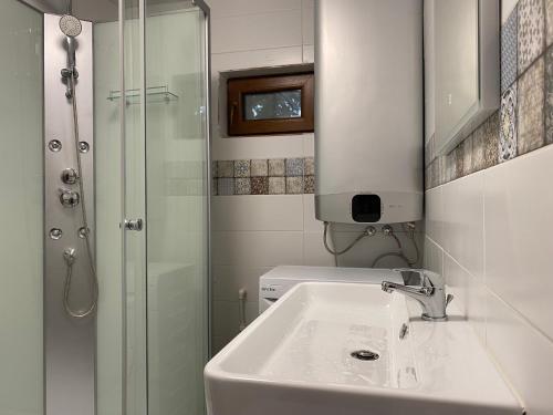 a white bathroom with a sink and a shower at Căsuța de la Cheia in Cheia