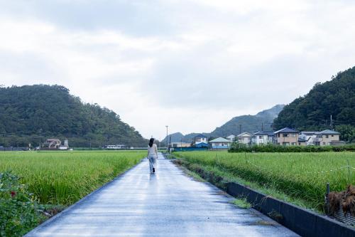 a woman walking down a path in a field at 1日1組限定!一棟貸し古民家 l Ginryotei 吟漁亭 in Matsuzaki