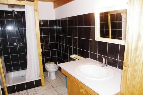 uma casa de banho com azulejos pretos, um lavatório e um WC. em Location de vacances en Bretagne sud em Névez