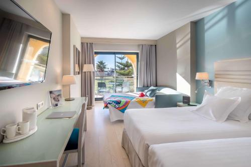 a hotel room with two beds and a desk at Barceló Costa Ballena Golf & Spa in Costa Ballena